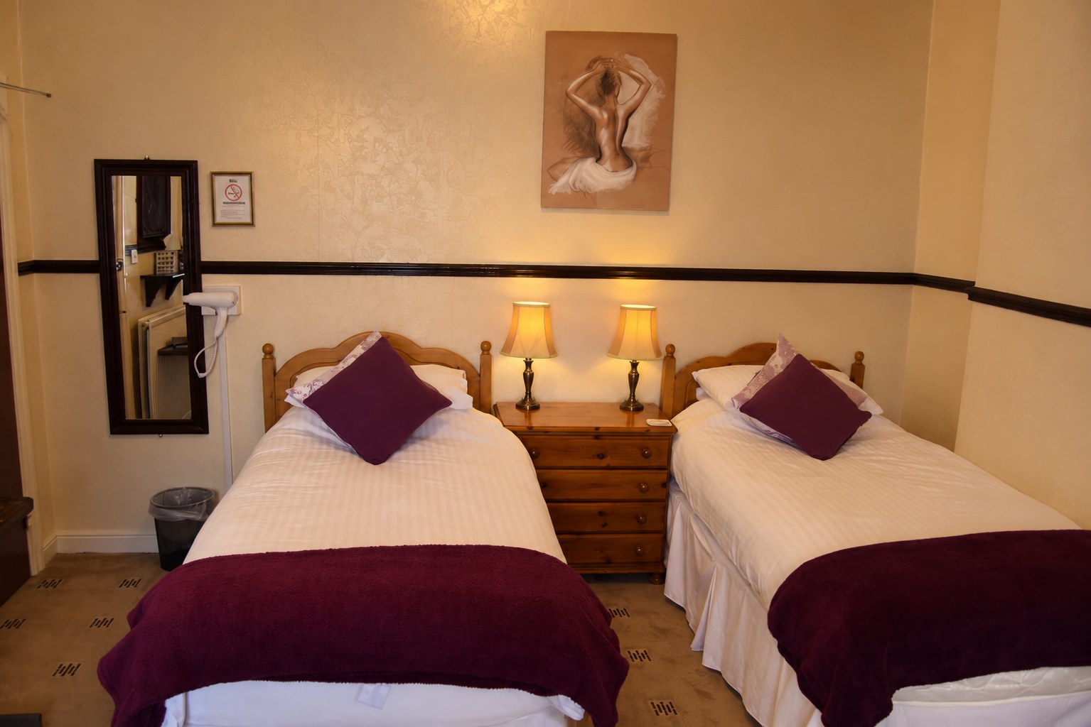 A classic twin room with two single beds, warm wood and lamplight